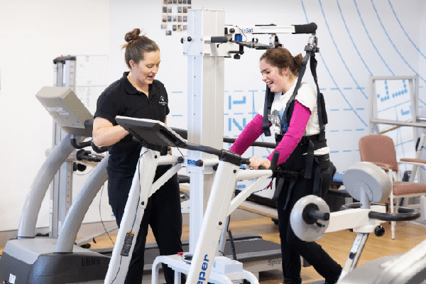 A girl using bodyweight supported treadmill training in the gym with her exercise physiologist