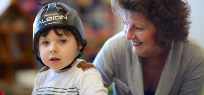A young boy wearing headgear with a therapist