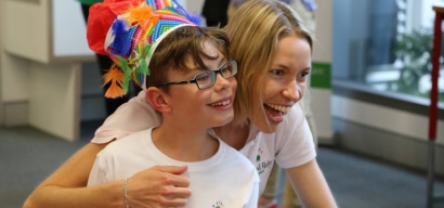A young boy wearing a craft hat smiling and smiling with his mum