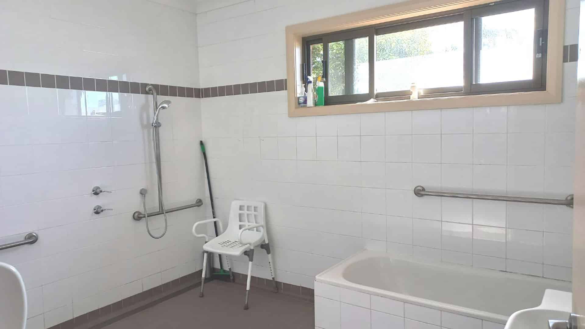 A bathroom with a shower area and bath under a window.