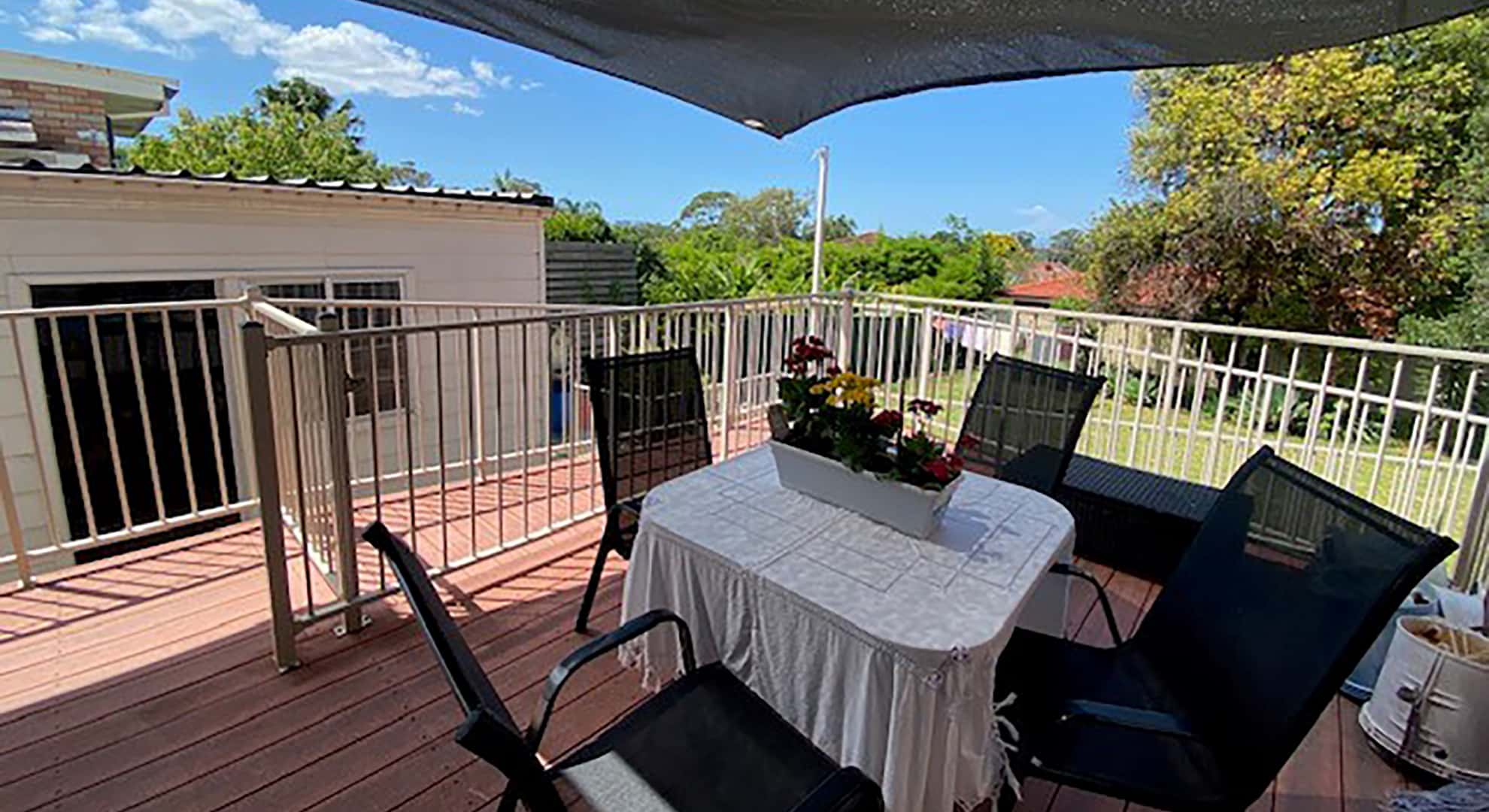 The shaded deck area with a gated ramp that travels down to a grassed back yard.