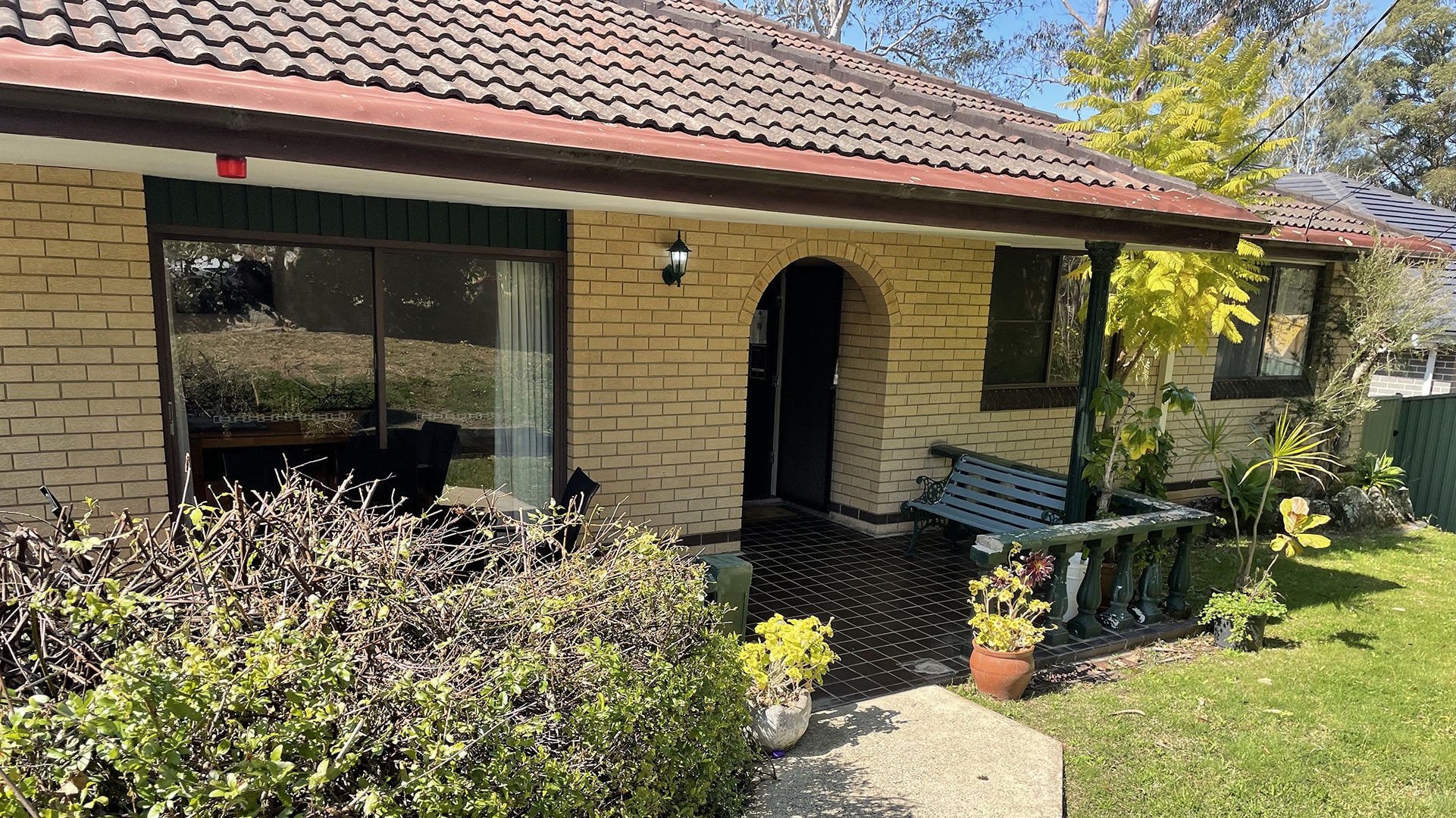 Front of the Normanhurst 3 property, a light coloured brick single story home with a tiled undercover area in front and a small grassed front yard