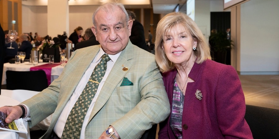 an older male and female, sitting smiling to camera at an event