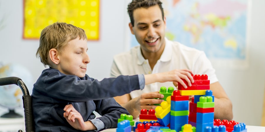 a young client playing with block with a support person