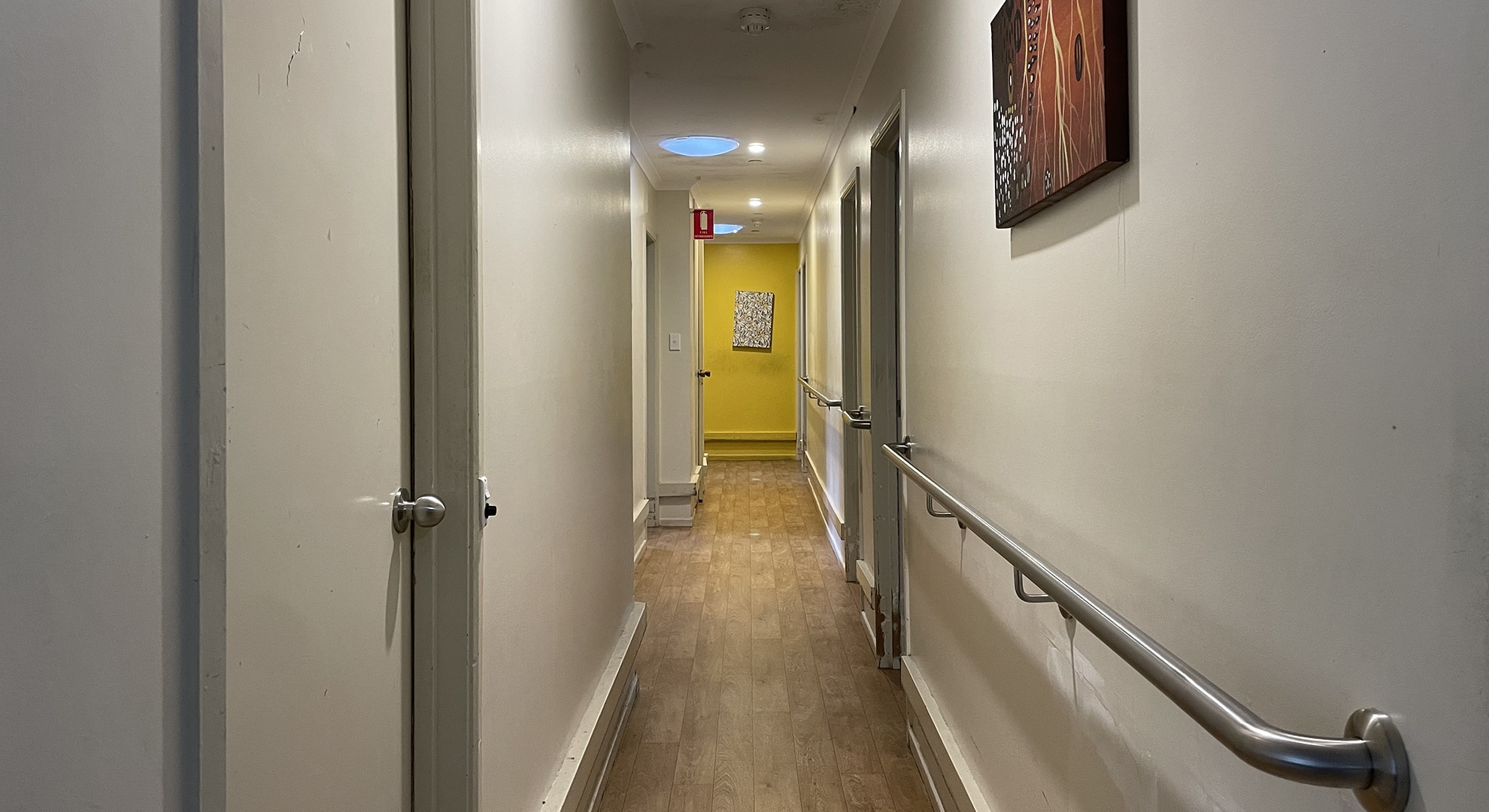 The view down a hallway with handrails and wooden floorboards