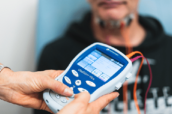 A vitalStim device with electrodes attached to an adult male.