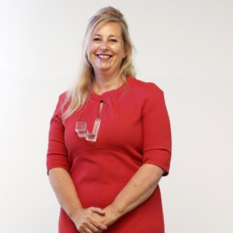 Professor Iona Novak in a red dress smiling to camera