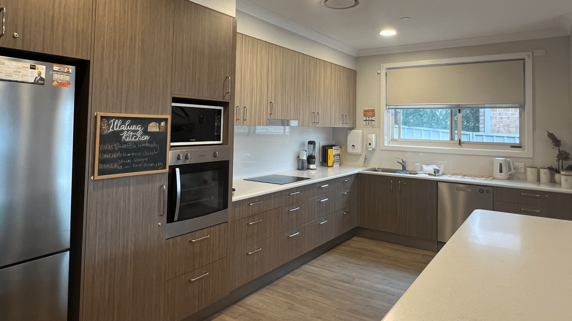 View of the kitchen with a window, brown cabinetry and stainless steel kitchen appliances