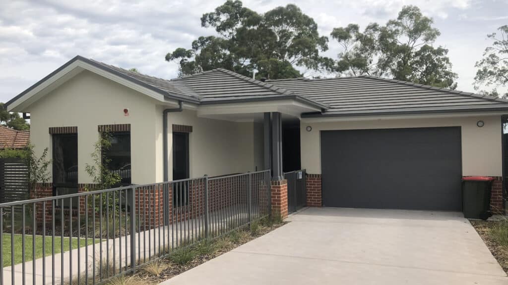 Front view of the house with secure garage and gated front yard.