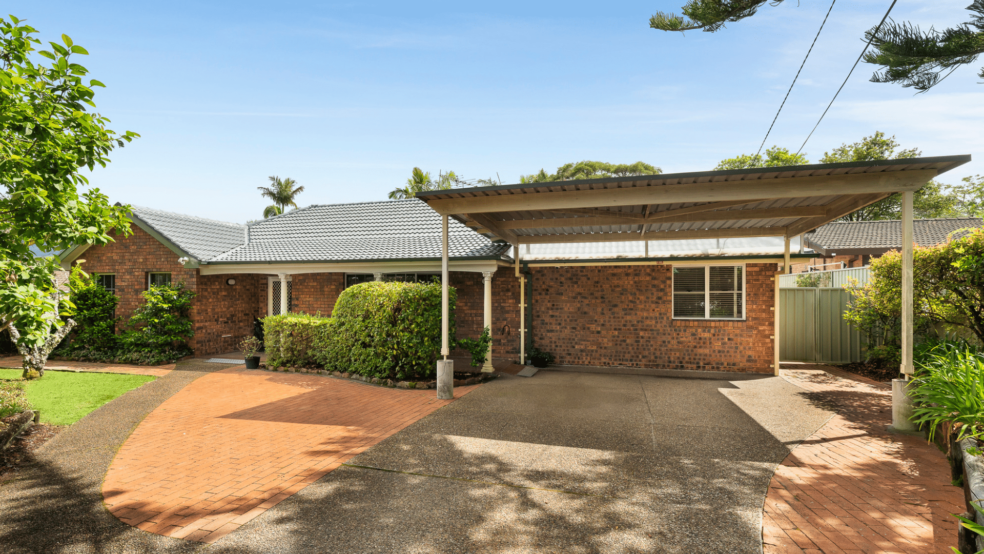 Front view of single-storey supported independent living home with wide covered driveway, step free access into the home and front garden