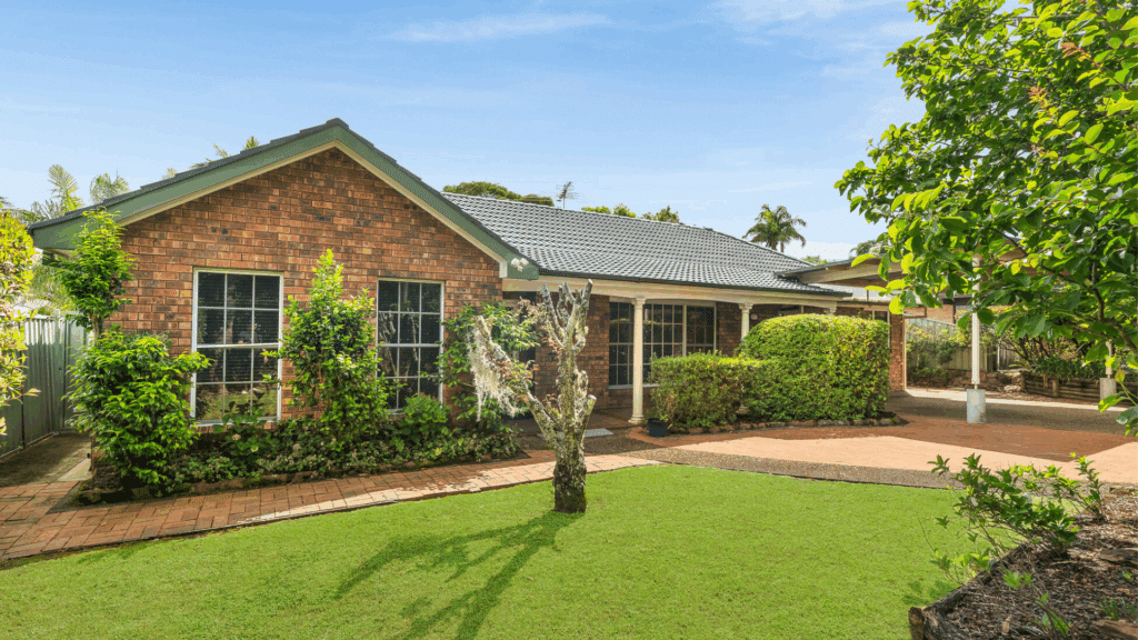 Front view of single-storey supported independent living home with wide covered driveway, step free access into the home and front garden