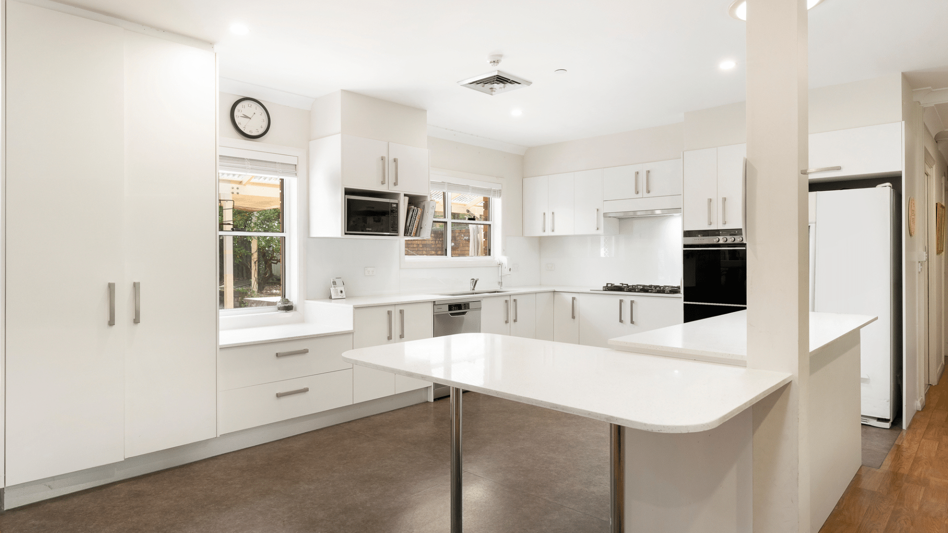 Open plan white kitchen that connects to the living space with a lowered benchtop in one section