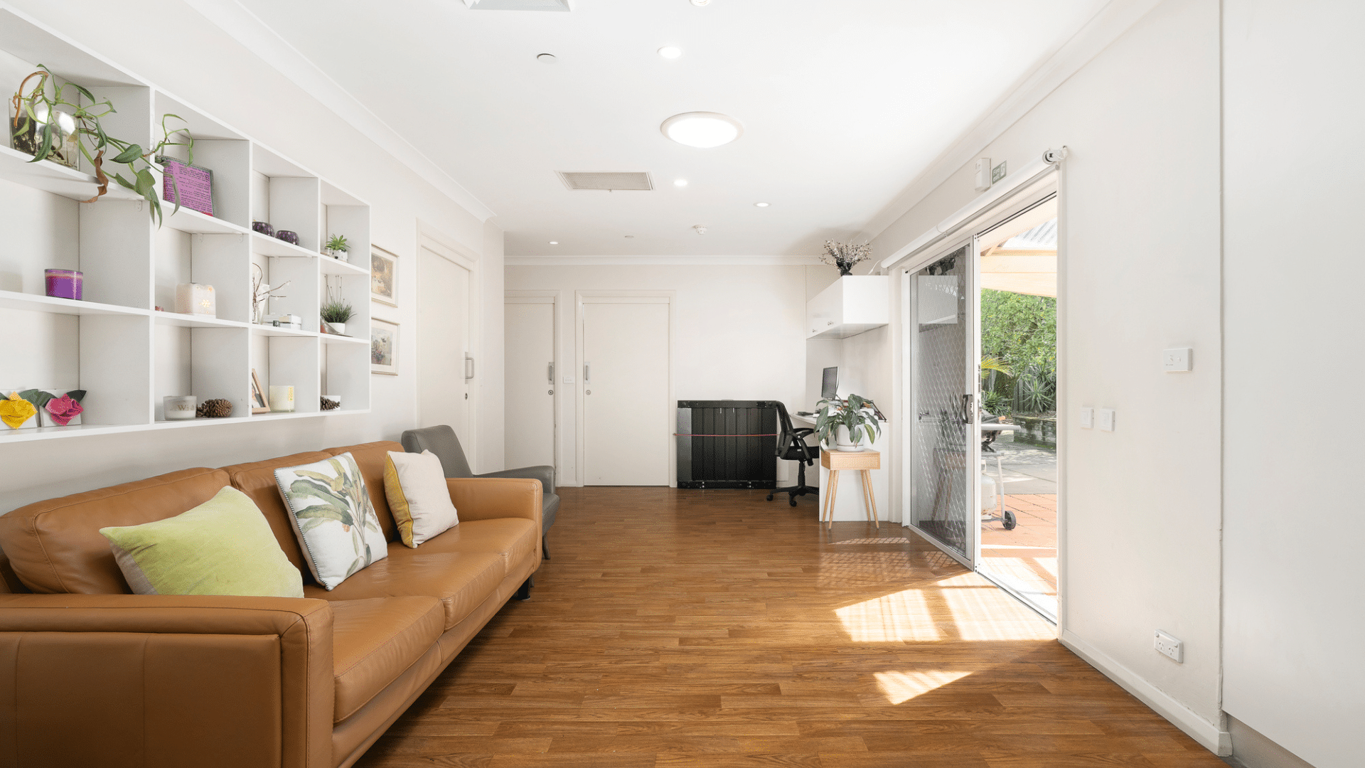 Living room with a couch and study area and a wide sliding door that connects to the backyard