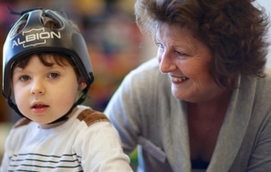 A young boy wearing protective headgear with a therapist