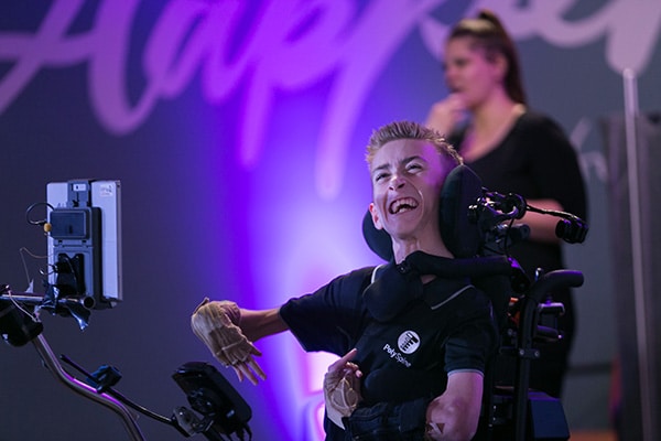Young man sitting in a wheelchair, smiling at a Remarkable event