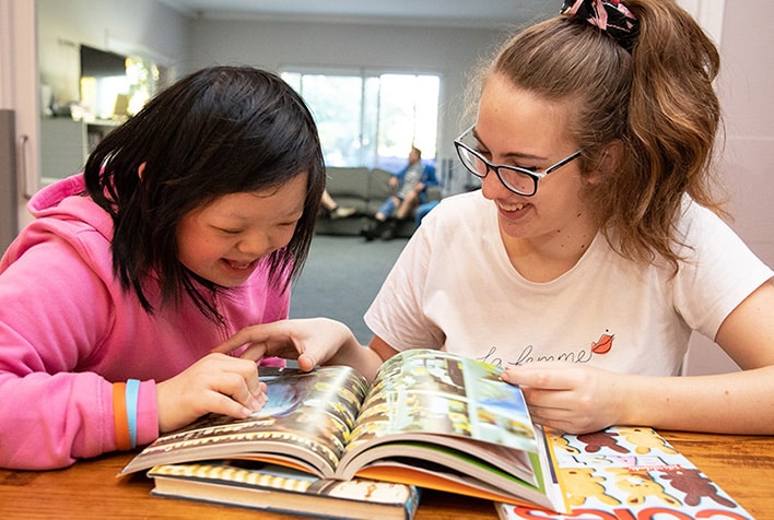 Two young girls reading a book together