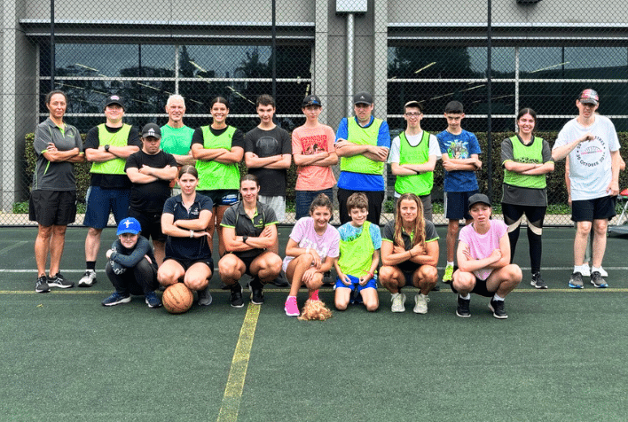 A group of multi sport participants posing with therapists on a tennis court