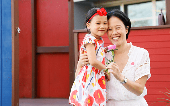 Asian girl with her mother holding a flower in the playground