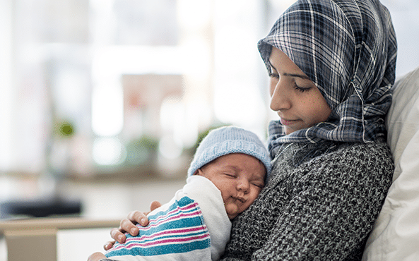 A mother wearing a hijab holding her bay in her arms