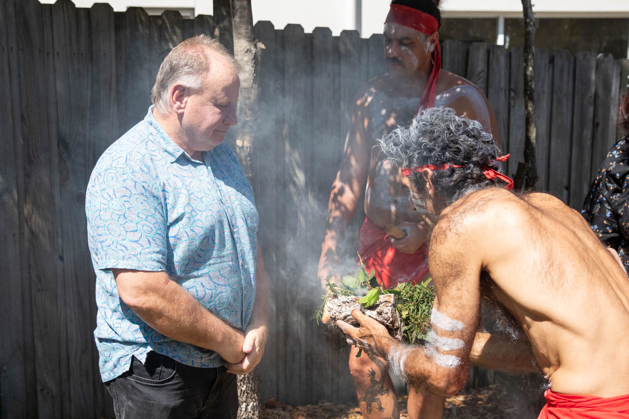 Two Aboriginal men and a white man participating in a traditional smoking ceremony