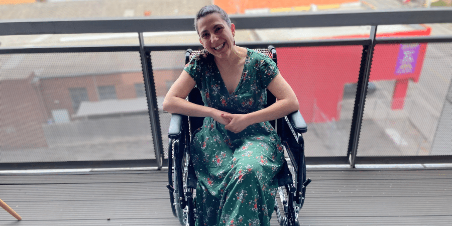 Laura Pettemuzzo, a woman with dark hair sitting in a wheelchair wearing a green dress, smiling.
