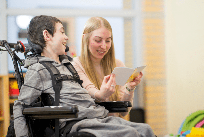 an career reading a book to a boy in a wheelchair