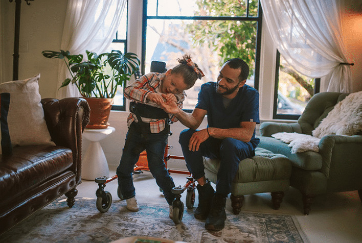 a father with his daughter standing in a walking frame in their living room