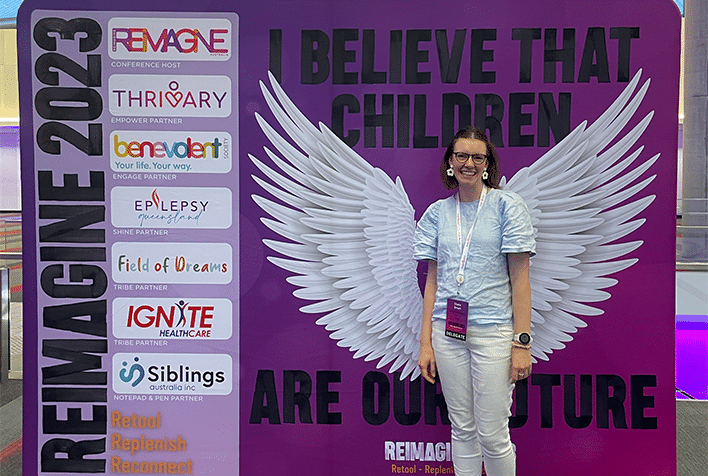 Claire Smart posing in front of signage at the Reimagine conference