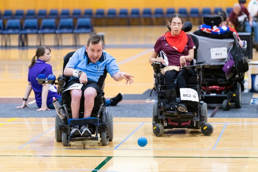 Participants playing wheelchair boccia in a gym