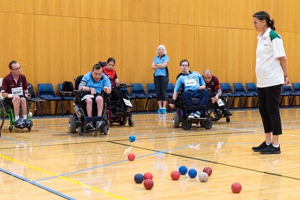A group of people participating in a game of wheelchair boccia