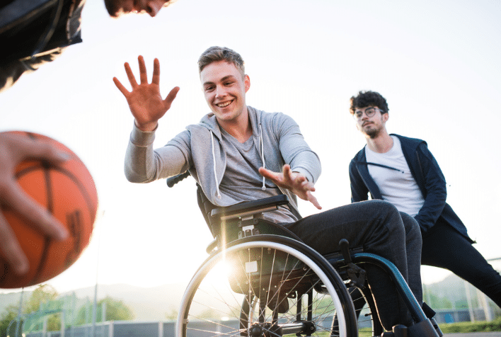 A group of males taking part in a game of basketball, one is using a wheelchair.