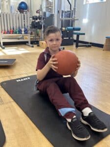 boy sitting in a gym holding a football