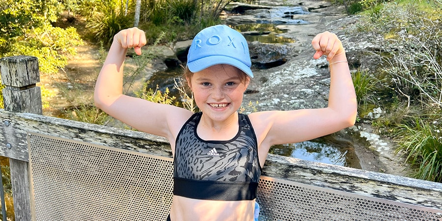 Sporty ten year old girl smiling and showing her muscles.