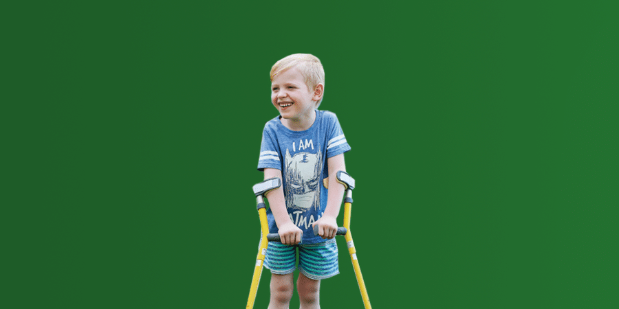 A young boy standing using walking supports
