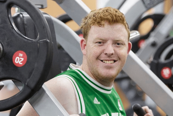 An adult male smiling while using gym equipment