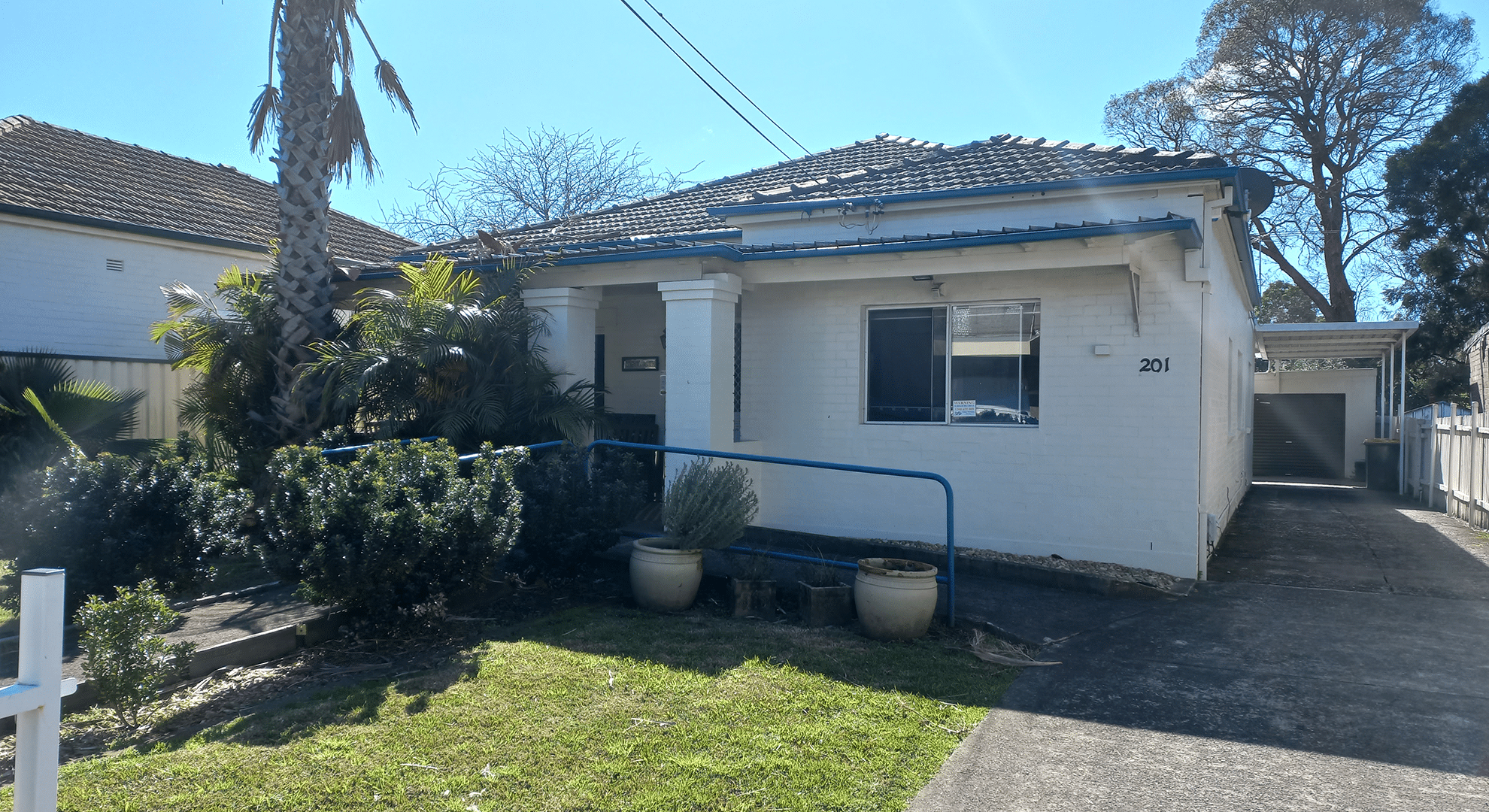 View of the front of the single story brick home with front garden, driveway and lock up garage at the rear of the property.