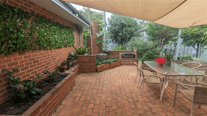 View of the outdoor dining area. Surrounded by plants and garden beds.
