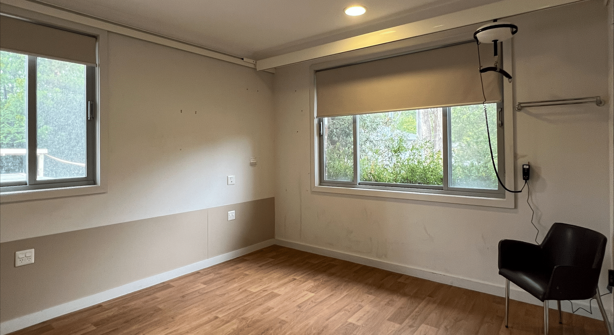 The empty bedroom with large windows and wooden floorboards.