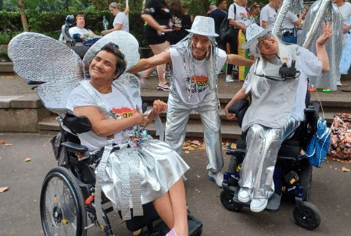 three people, two in wheelchairs dressed in white and silver