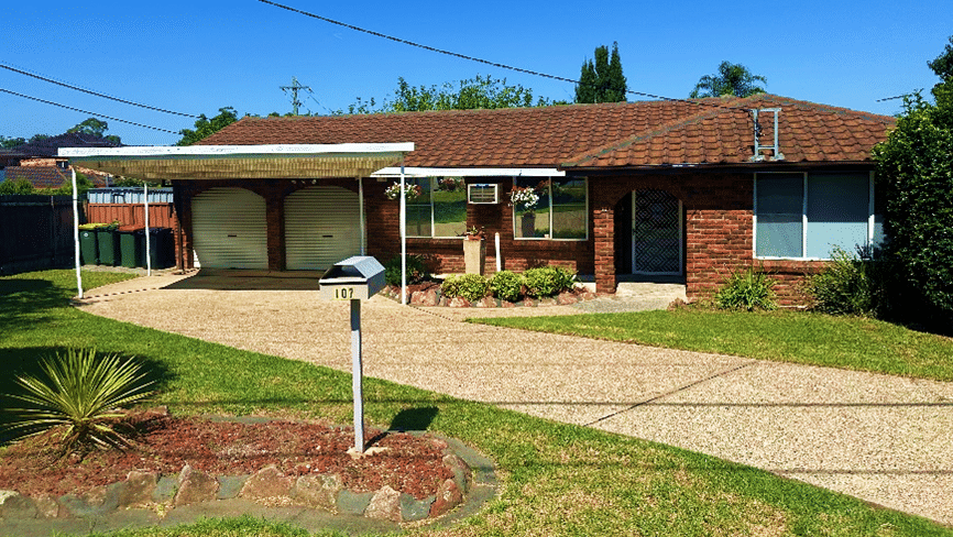 Front view of single story brick home with double lock up garage and front garden.