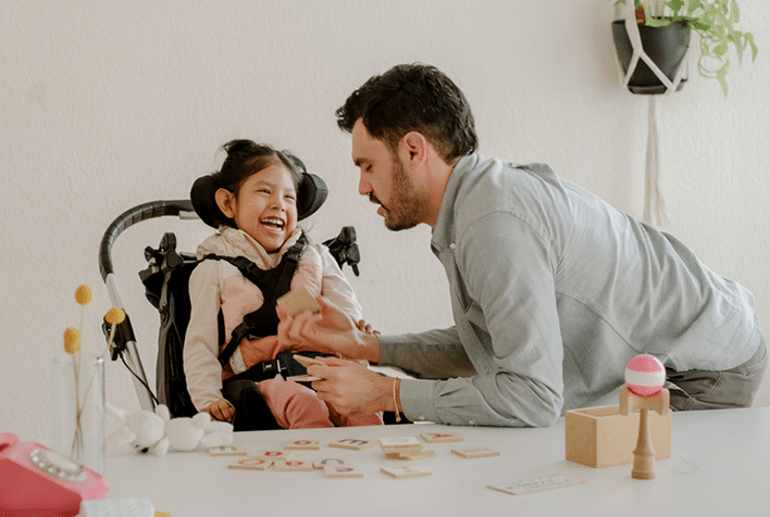 A father playing games with his smiling daughter in a wheelchair