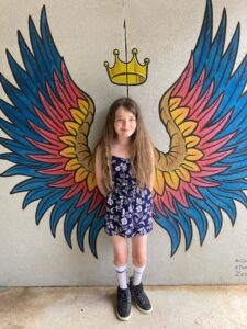 Girl standing against a wall with angel wing graphic