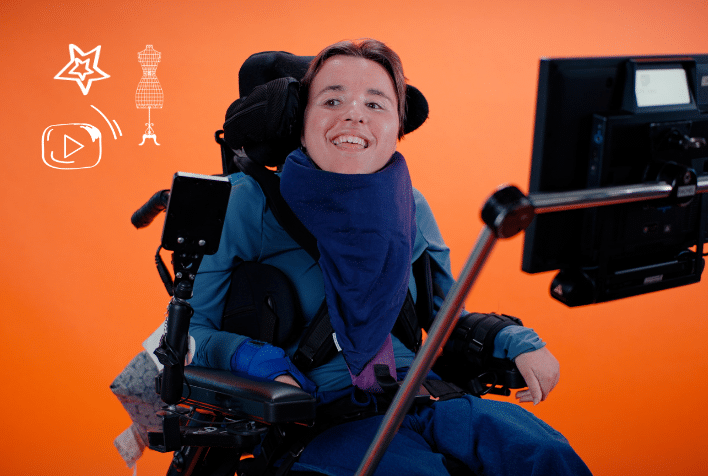 White woman with short dark hair in wheelchair on orange background