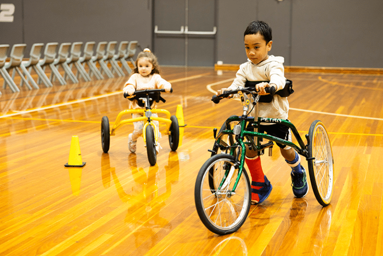 Two young children using frame runners in a gym