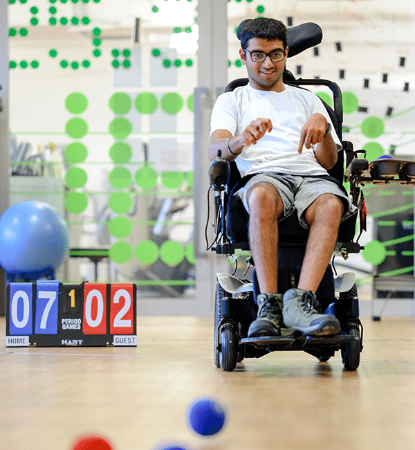 A young adult male wheelchair user playing boccia