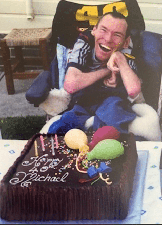 Michael smiling in front of a cake on his 40th birthday