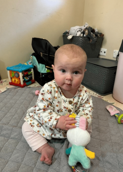 Baby Sadie sitting on the floor playing with toys at a therapy appointment