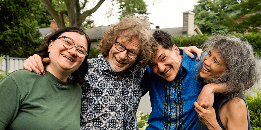 Portrait of a multiracial family outdoors in summer. Senior parents are in their sixties, children are young adults. Son is living with a disability; cerebral palsy.