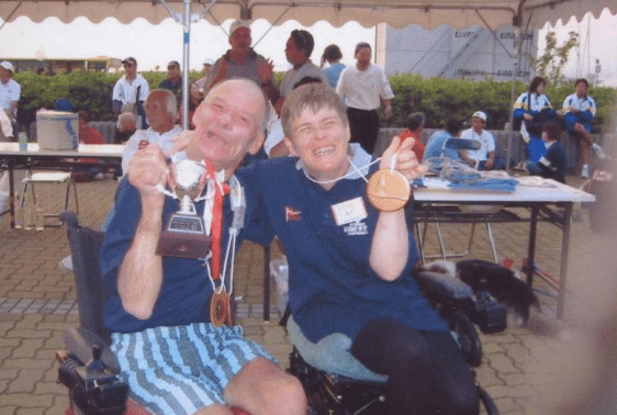 Lindsay and Maria smiling holding up a trophy and a medal