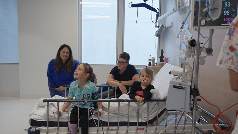 Zara sittig on the bed with her family during cord blood treatment